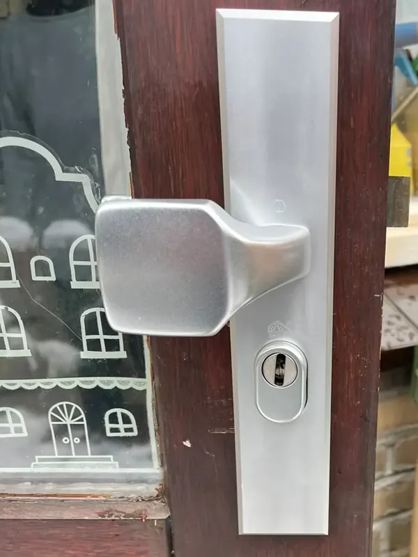 Aluminium veiligheidsbeslag met vaste knop en een kerntrekrozet om de cilinder, op een houten deur met glas